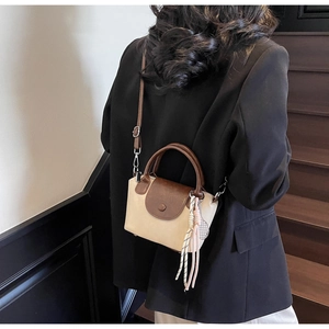 Detail of the chic beige and coffee leather crossbody bag with woven tassel pendant