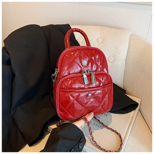 Detail of red quilted leather crossbody bag featuring silver flower charm and chain strap