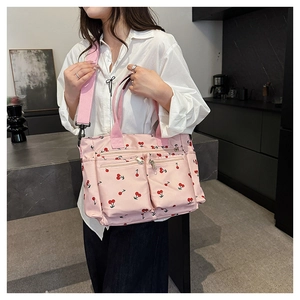 Détail du sac cabas rose imprimé cerises avec plusieurs poches et bandoulière en tissu