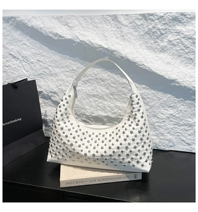 Detail view of white crescent bag with silver studs on a premium minimalist background