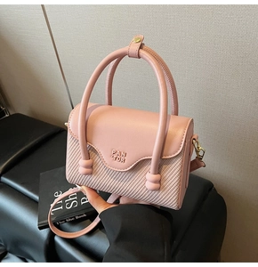 Détail du sac bandoulière rose clair avec texture tissée, poignée en métal et logo