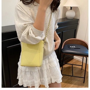 Close-up of yellow litchi grain leather bucket bag with chain strap and stitched details