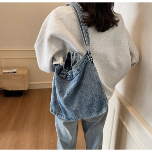 Detail of blue denim tote bag with magnetic snap closure and adjustable wide strap