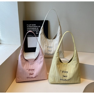 Detailed display of three pleated hobo bags in pink, beige and yellow with heart prints