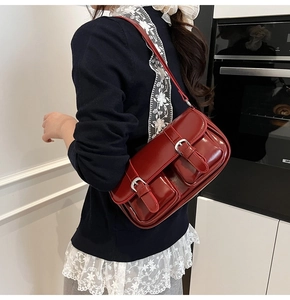 Detail view of red patent leather shoulder bag with glossy finish and silver metal buckles