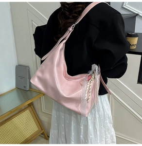 Detail of pink patent leather hobo bag with white lace charms and glossy finish