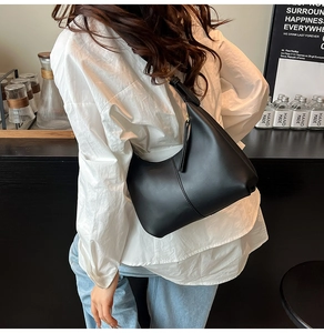 Detail of black leather crescent shoulder bag with central seam and zip closure