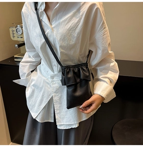 Détail du petit sac seau noir plissé avec bords volantés et texture en cuir litchi