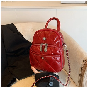 Detail of red quilted mini crossbody bag with flower logo and silver chain strap