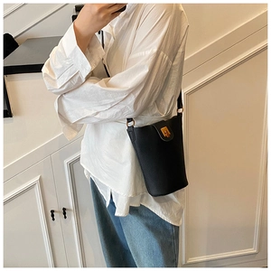 Detail of black lychee grain leather bucket bag featuring gold metal hardware and strap