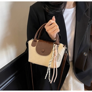 Detail of beige mini crossbody bag with tennis racket charm and colorful tassel rope