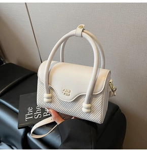 Détail d'un sac bandoulière crème en cuir tressé avec le logo métallique PAN TOR