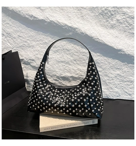 Detailed macro view of black hobo bag with polished silver punk rivets on shiny leather