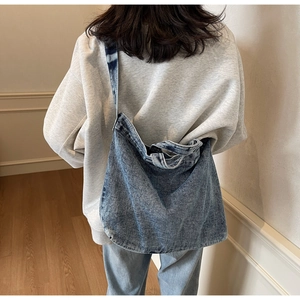 Detailed view of the vintage washed blue denim tote bag worn with a casual gray hoodie