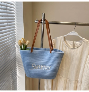 Détail d'un sac cabas tissé bleu avec broderie Summer et anses en cuir marron