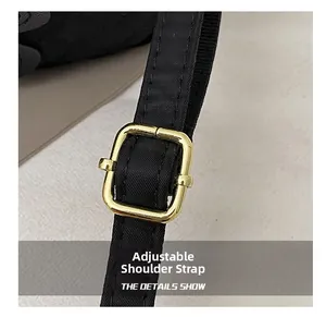 Detail of adjustable black nylon shoulder strap with gold metal buckle and neat stitching