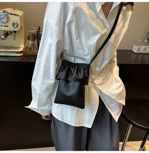 Gros plan d'un mini sac bandoulière noir texture litchi avec détails volantés
