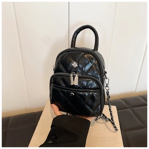 Detail of glossy black quilted mini bag with floral metal accent and chain strap