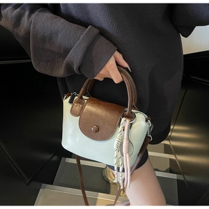 Detail showing mint green and brown leather handbag with woven rope keychain pendant