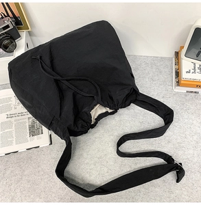 Vue détaillée du sac à bandoulière noir avec cordon et accessoires lifestyle