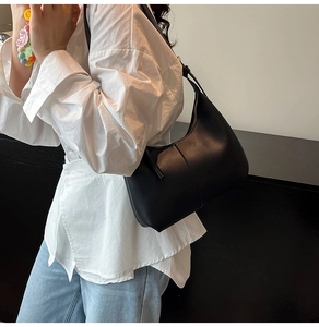 Minimalist black leather hobo bag worn by a model in casual attire for a modern look
