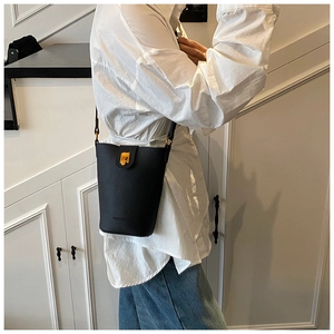 Close-up of black bucket bag featuring grainy leather texture and gold metal clasp