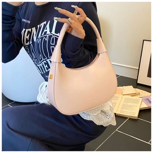 Dettaglio della borsa a mezzaluna rosa con texture in pelle di qualità e logo impresso
