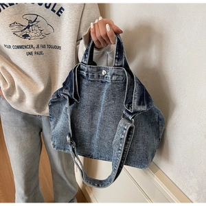 Detail shot of the vintage washed denim tote bag with textured blue fabric and metal buckle
