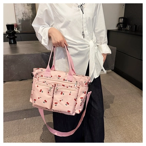 Détail du sac cabas rose à imprimé cerise avec poches zippées pratiques à l'avant