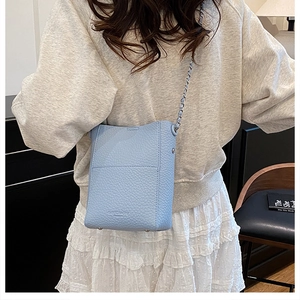 Close-up of light blue bucket bag with lychee grain leather and silver chain strap
