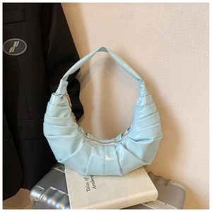 Close-up of light blue pleated croissant bag with smooth texture and metal zipper detail