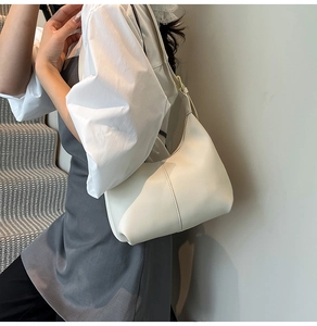 Detailed side view of off-white faux leather hobo bag with adjustable strap and gold hardware
