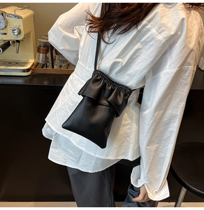 Détail du sac seau noir avec bordure à volants et texture en cuir à grain de litchi