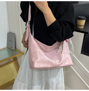 Detail of pink patent leather hobo bag with adjustable wide strap and silver hardware