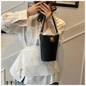Close-up of black leather bucket bag with gold twist lock closure and fine strap