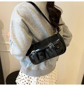 Close-up of black glossy PU leather crossbody bag with dual pockets and silver buckles
