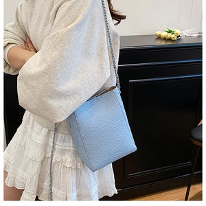 Detail of light blue bucket bag showing premium lychee texture and slim chain strap
