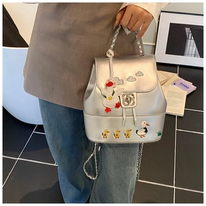 Detail eines silbernen Mini-Rucksacks mit Enten-Stickerei und Rosen-Metallverschluss