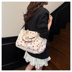 Détail du sac cabas blanc à imprimé cerises avec plusieurs poches zippées pratiques