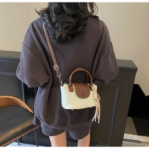 Detail of color-block crossbody bag with brown handle and white faux leather body