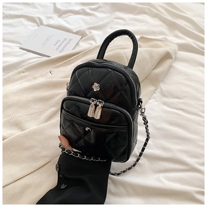Detail of black quilted mini bag with floral ornament and silver chain strap