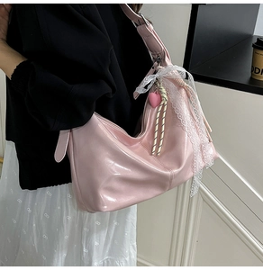 Pink patent leather shoulder bag with white lace trim and heart charm detail