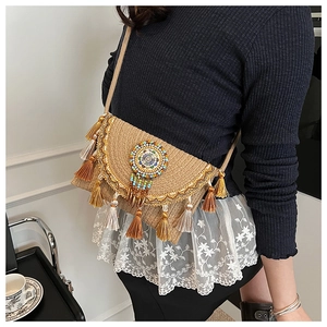 Detail of bohemian straw envelope bag with colorful silk tassels and bead embroidery