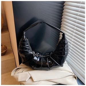 Detailed view of the pleated black crescent bag texture with glossy finish and metal zipper