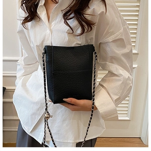 Detail of black pebbled leather bucket bag with silver ball buckle and chain strap