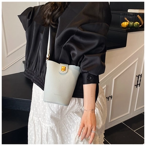 Fashion light blue leather bucket bag worn as a crossbody purse in a modern home setting