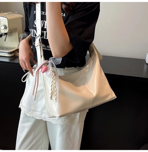 Close-up of a white crescent shoulder bag with heart pendant and lace bow decorations