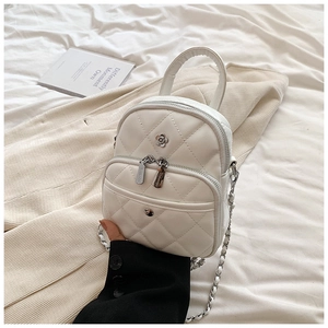 Detailed close-up of white quilted mini bag with silver chain strap and flower logo