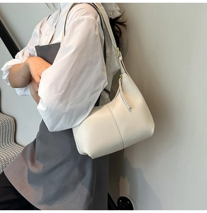 Detail view of a cream shoulder bag featuring central seam stitching and leather texture