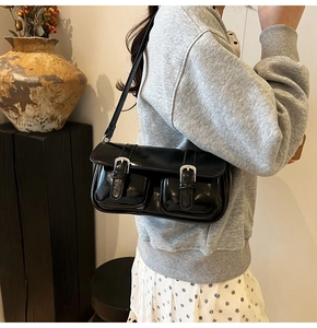 Detail showing shiny black patent leather surface and dual pockets with silver buckles